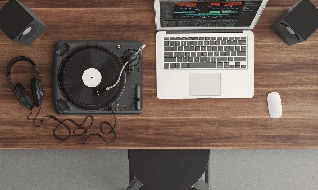 An old record player sits beside a laptop which is showing a music recording application. An example of building your digital life  