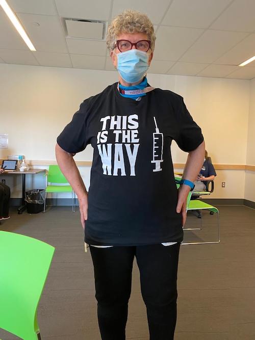 Covid 19 vaccine - A medical professional wearing a t-shirt which reads This is the way beside a image of a syringe